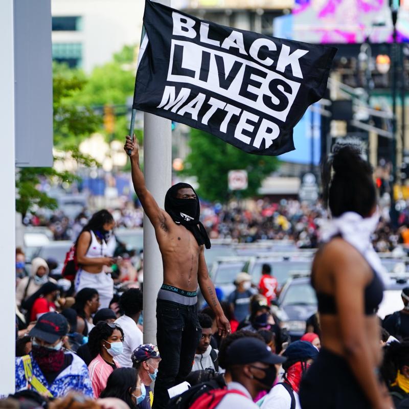 Protestors wave Black Lives Matter flags in the aftermath of George Floyd's death in policy custody.